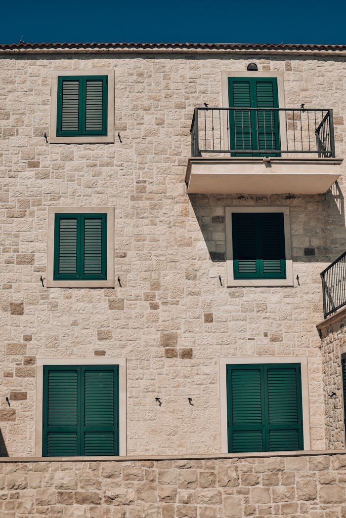 Stone building with green shutters and a balcony